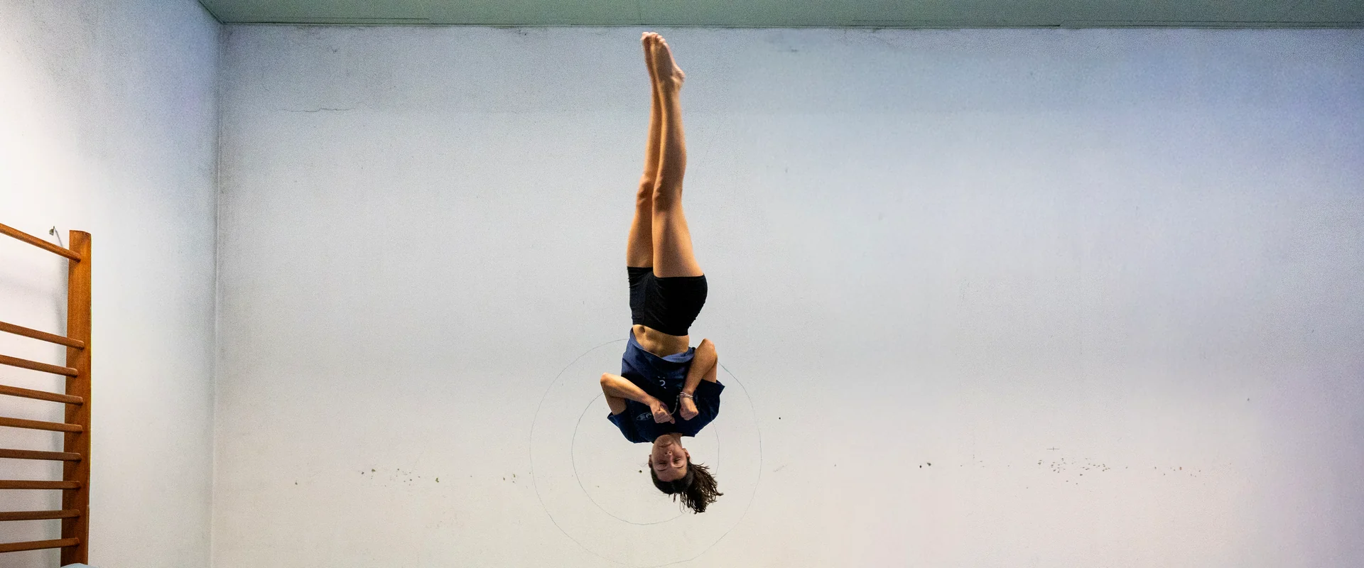 Ginasta do clube em pleno salto de trampolim, invertida no ar